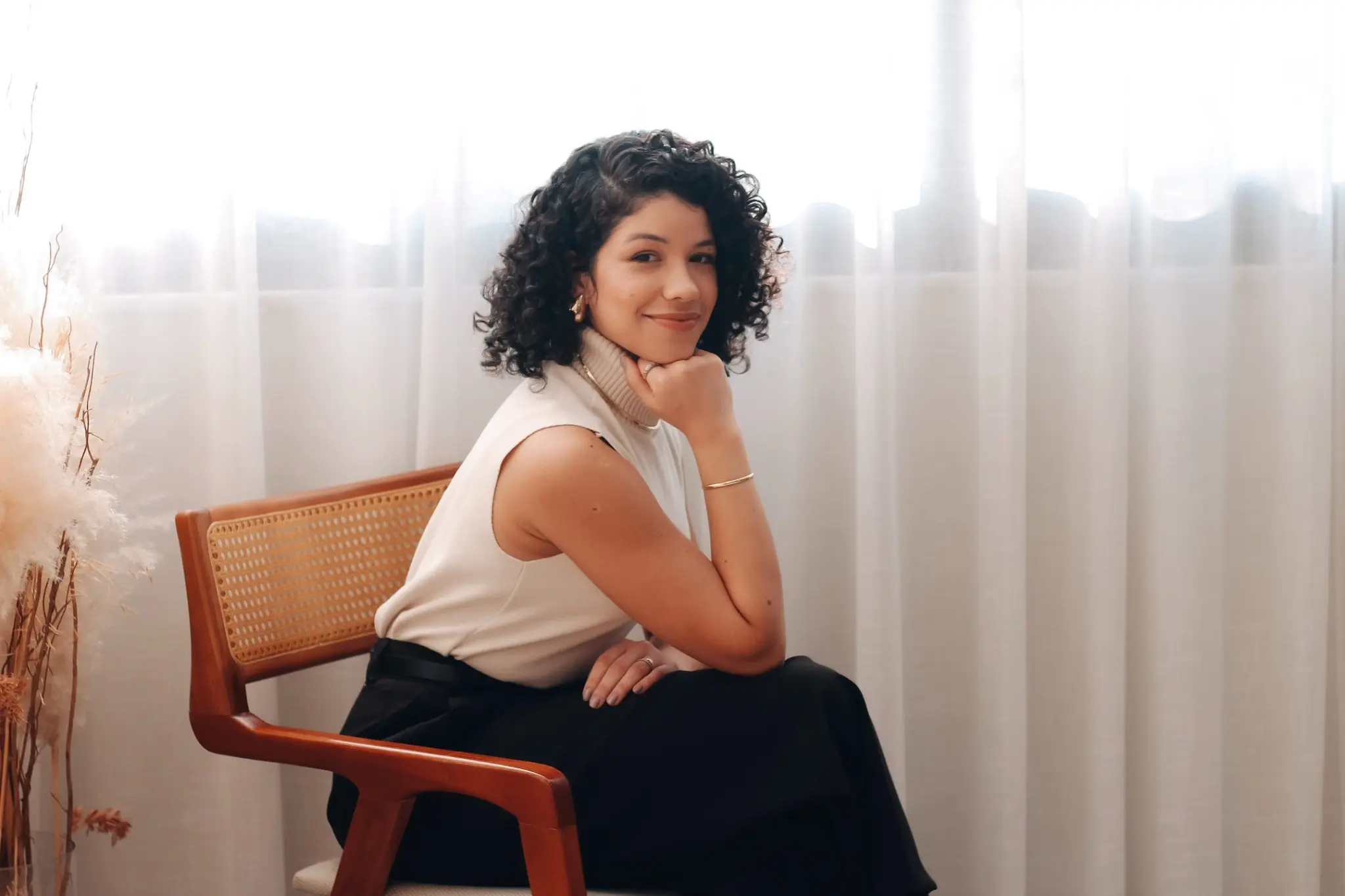 Najla Basso sentada, sorrindo para a câmera